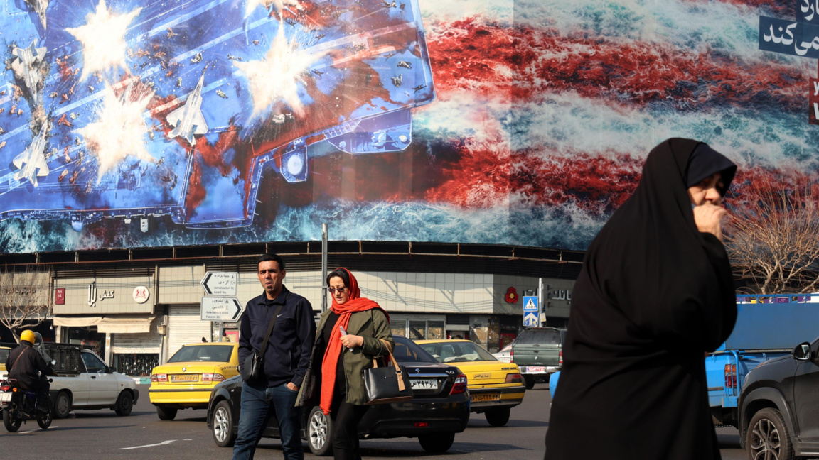 Иранци минават покрай огромен антиамерикански билборд, окачен в Техеран, 27 януари 2026 г.
